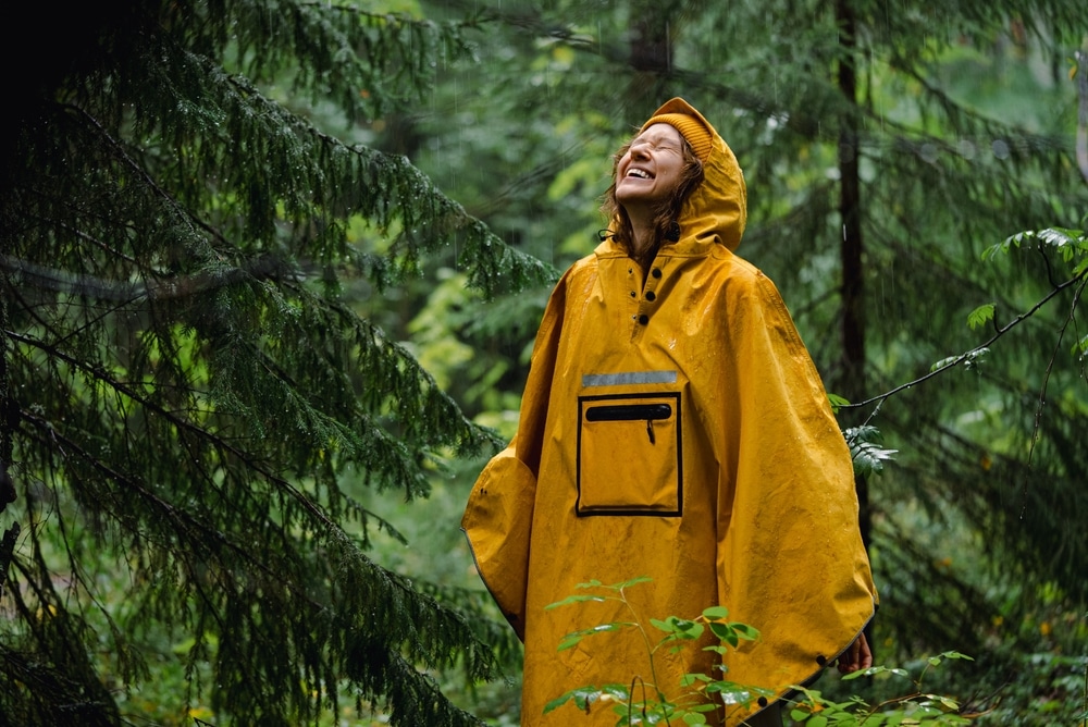 A joyful woman in a yellow rain poncho hikes through the Bandon National Wildlife Refuge.