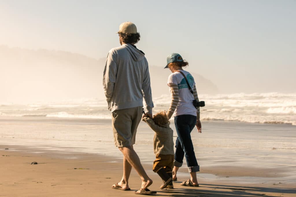 Family walks hand in hand on beach on their Oregon Coast vacation